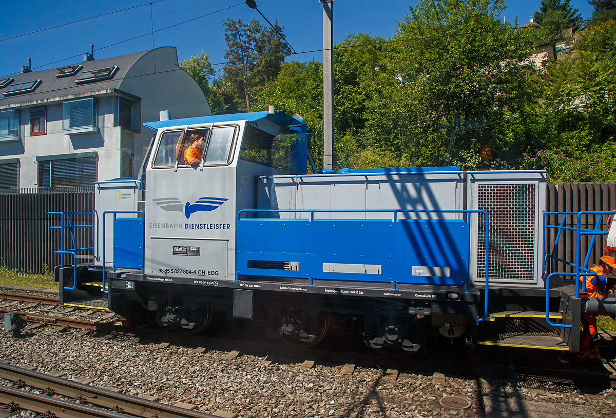 Aus dem Zug heraus konnte ich am 11.07.2022 bei Liestal die Em 837 804-4 (98 85 5837 804-4 CH-EDG, eine dreiachsige dieselelektrische MaK DE 502 der EDG - Eisenbahndienstleister GmbH, bei Rangierarbeiten erwischen. 

Die dreiachsige dieselelektrische MaK DE 502 wurde 1986  von der Krupp MaK Maschinenbau GmbH in Kiel gebaut, die elektrische Ausrüstung ist von BBC (Brown, Boverie & Cie. AG). Im Mai 1987 ging die Lok in die Schweiz an die Moos Stahl AG in Emmenbrücke (ab 1993 Panlog AG). Im Februar 2017 ging sie an die EDG - Eisenbahndienstleister GmbH in Thayngen. 

Nach den Fortschritten in der Entwicklung der Drehstrom-Antriebstechnik wurde 1980 erstmals eine dreiachsige Lok mit elektrischer Leistungsübertragung im dritten Typenprogramm angeboten. Ausgerüstet mit MTU-Motoren des Typs 6V 331 TC12 bildet sie das Pendant zur G 761 C.

Als dann ab 1981 die neuen Motoren der Reihe 396 zur Verfügung standen wurde bei den dieselelektrischen Loks die Typenbezeichnung in DE 502 geändert. Zusätzlich wurde die elektrische Ausrüstung auf den aktuellen Stand der Technik gebracht.

Von der Standardausführung wichen einige Loks beider Typen ab, die mit MWM-Motoren ausgerüstet wurden. Geliefert wurden sie an die Ruhrkohle AG und an BASF.

TECHNISCHE DATEN der DE 502:
Anzahl:  13 (7 mit MTU und 6 mit MWM Motoren)
Spurweite:  1.435 mm (Normalspur)
Achsformel:  Co
Länge über Puffer:  9.870 mm
Höhe:  4.220 mm
Breite:  3.100 mm
Gesamtradstand:  3.800 mm
Treibraddurchmesser:  1.000 mm
Kleinster bef. Halbmesser:  40 m
Dienstgewicht:  60 t
Höchstgeschwindigkeit:  45 km/h (einen und geschleppt)
Installierte Leistung:  560 kW (bei 1.800 U/min)
Anfahrzugkraft: 255 kN
Motorentyp:  MTU 6V336TC13 (V 6 Zylinder Dieselmotor)  
Leistungsübertragung:  elektrisch  (Hersteller  BBC)
Tankinhalt:  1.700 l