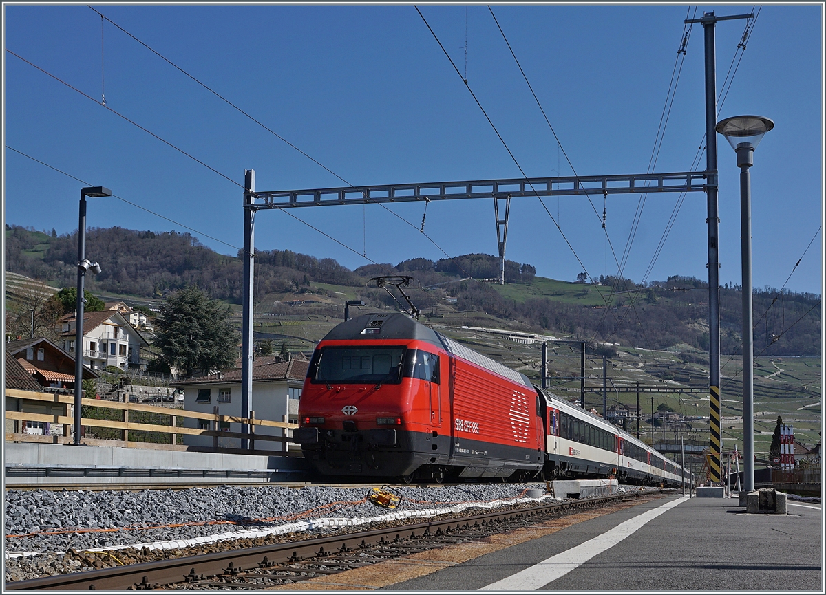 Eine SBB Re 460 schiebt am ersten Betriebstag des Umbau bedingt verschwenkten Gleises 1 in Cully einen IR 90 in Richtung Brig.
Das Bild zeigt deutlich, dass das Gleis nicht nur nach Norden verschwenkt wurde, sondern auch höher liegt als vorher (als Referenz dient das Gleis 2 in der Bildmitte). 

1. April 2021