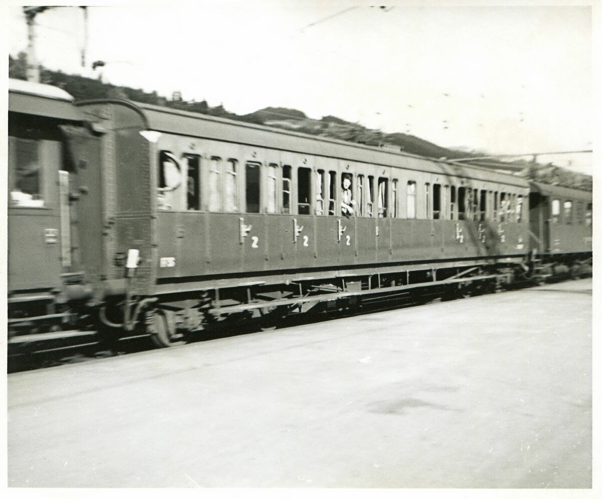 Um 1963 in Thun aufgenommen: Extrazüge für die weihnachtliche Rückkehr (oder Rückkehr zur Ausübung des Stimmrechts) der italienischen Arbeiter waren aus den abenteuerlichsten Wagen zusammengesetzt. Hier ein typischer Carozza Centoporte ( hunderttüriger Wagen ) der FS Italia; solche Wagen wurden offenbar zswischen 1928 und 1951 gebaut. Davor scheint ein alter SBB-Platformwagen eingereiht zu sein.   