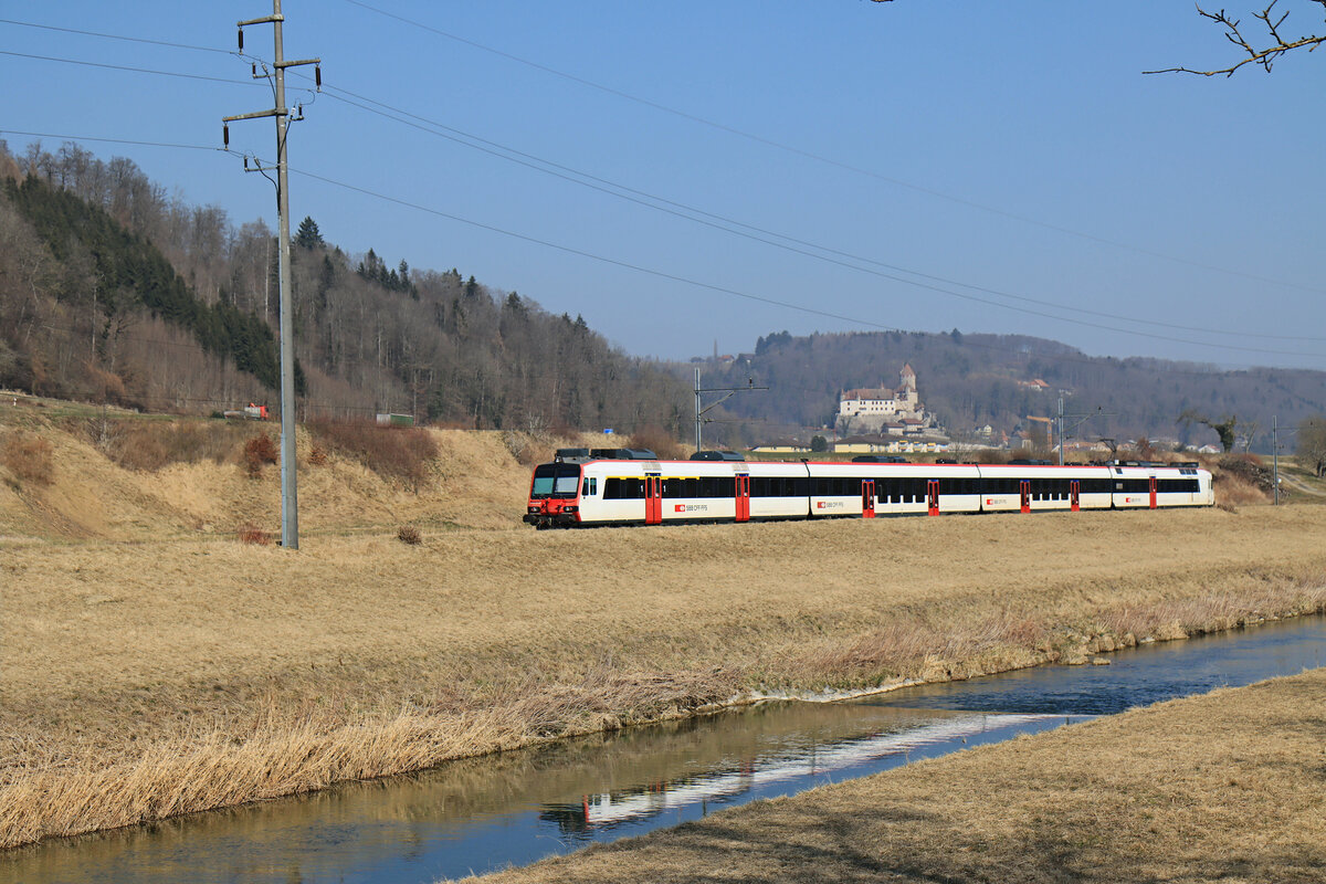 Vor Lucens an der Broye, zwischen Moudon und Payerne: Von hier ergibt sich eine schöne Sicht auf die Burg Château de Lucens, administratives und gerichtliches Zentrum der Herrschaft von Bern über die Waadt (Vaud) zwischen 1536 und 1798 (noch immer prangt das Berner Wappen an der Aussenmauer). Es fährt ein Domino-Zug der S9 (Lausanne - Palézieux - Payerne - Kerzers) durch. (Wagen: ABt 39-43 823 - B 29-43 151 - B 20-43 013 - RBDe 560 265). 10.März 2022  