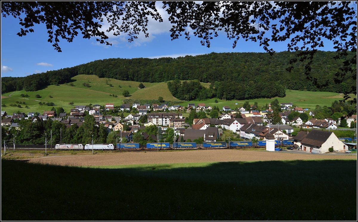 Zwei Crossrail-Traxx 2E in Tecknau, eine Maschine im Macquarie-Anstrich und die zweite mit Crossrail-Logo versehen, ziehen einen LKW-Walter-Zug richtung Basel. Juli 2016.