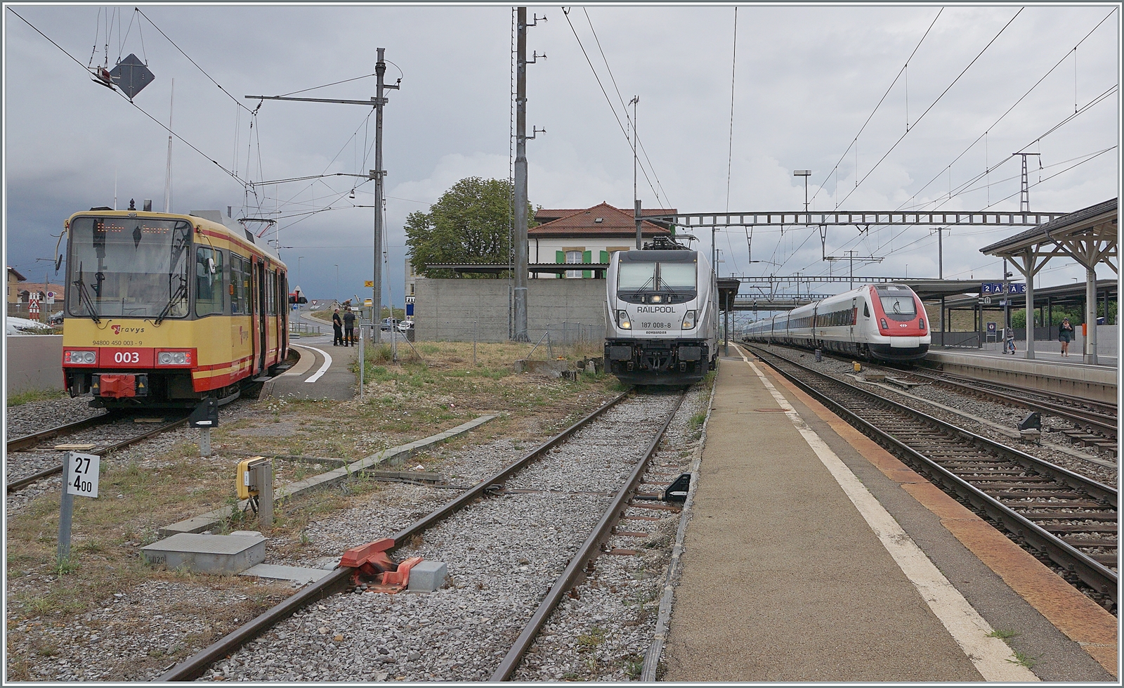 Bunte Bahn in Chavornay: Links wartet der TRAVYS/OC Be 4/8 003 auf die Abfahrt nach Orbe, in der Mitte die an die BLS vermietete RailPool 187 008-8 auf ihre Güterlast und rechts im Bild fährt ein SBB ICN RABDe 500 als IR 5 auf den Weg von Lausanne nach Zürich ohne Halt durch Chavornay. 

15. August 2022