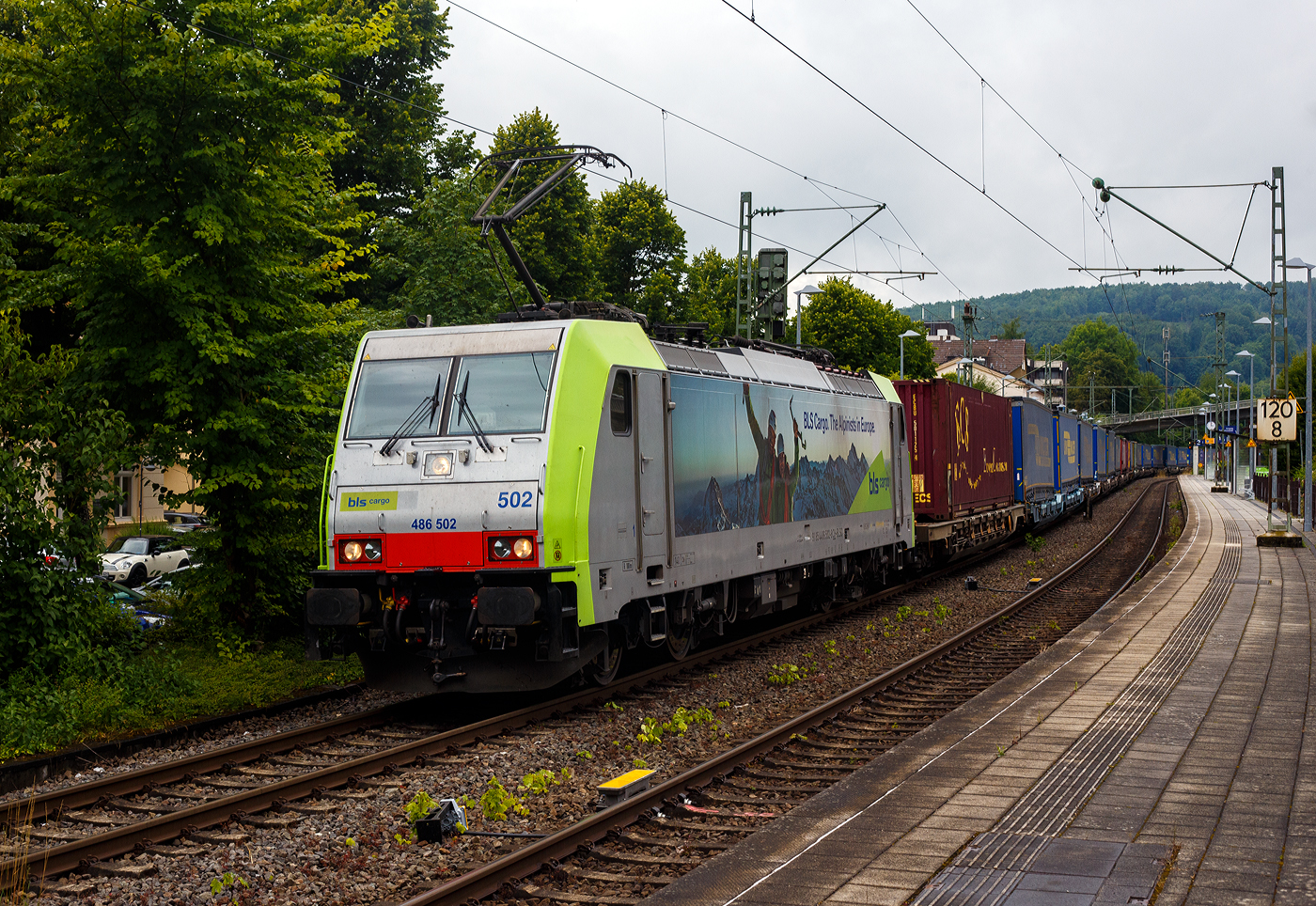 Die BLS Cargo 502, Re 486 502-8/E 486 502 SF  The Alpinists in Europa  (91 85 4486 502-8CH-BLSC) fährt am 07 Juli 2025 mit einem HUPAC KLV-Zug durch Kirchen (Sieg) in Richtung Köln.

Nochmals einen lieben Gruß an den netten Lokführer zurück.

Die TRAXX F140 MS wurde 2008 von Bombardier in Kassel unter der Fabriknummer 34401 gebaut und an die BLS Cargo AG (Bern) geliefert. Die Loks sind nur für die Schweiz, Deutschland, Österreich und Italien zugelassen.

Der Erfolg im Güterverkehr veranlasste die BLS zehn weitere TRAXX zu bestellen im Gegensatz zur ersten Serie TRAXX F140 AC1 mit der Bezeichnung Re 485 001 bis 485 020, die nur unter Wechselstrom fahren können, können die TRAXX F140 MS Re 486 501 bis 486 510 auch unter 3.000 Volt Gleichstrom eingesetzt werden. Bombardier hatte seit der ersten Lieferung Verbesserungen vorgenommen. Dabei wurde der Lokomotivkasten optimiert und die Traktionsausrüstung mit moderneren Komponenten versehen. Eine Nachbeschaffung wäre noch möglich gewesen, hätte aber dazu geführt, dass die Lokomotiven nicht auf dem neuesten Stand waren und nicht unter der Gleichstromfahrleitung eingesetzt werden konnten. Die eingebauten Zugbeeinflussungssysteme erlauben den Einsatz in Deutschland, Österreich, der Schweiz und Italien (DACHI). Anfänglich waren die Lokomotiven in der Schweiz nur für den Einsatz auf Strecken mit konventioneller Zugbeinflussung und nicht auf ETCS Level 2 Strecken zugelassen. Die Re 486 können unter sich und mit den Re 485 und Lokomotiven der Baureihe 185/186 in Vielfachsteuerung eingesetzt werden. Mittlerweile nach Umbauten durch die BLS, können die Loks nun auch mit Re 465, sowie mit Siemens Vectron der BR 193 bzw. Re 475 in Mehrfachtraktion gefahren werden.

TECHNISCHE DATEN:
Spurweite: 1.435 mm (Normalspur)
Achsformel: Bo’Bo’
Länge über Puffer: 18.900 mm
Höhe: 4.385 mm
Breite: 2.978 mm
Drehzapfenabstand: 10.400 mm
Achsabstand im Drehgestell: 2.600 mm
Dienstmasse: 85 t
Höchstgeschwindigkeit:  140 km/h
Dauerleistung: 5.600 kW
Dauerzugkraft: 300 kN
Treibraddurchmesser: 1.250 mm
Stromsysteme: 15 kV 16,7 Hz, 25 kV 50 Hz Wechselstrom sowie 3 kV und 1,5 kV Gleichstrom
Antrieb: Tatzlager