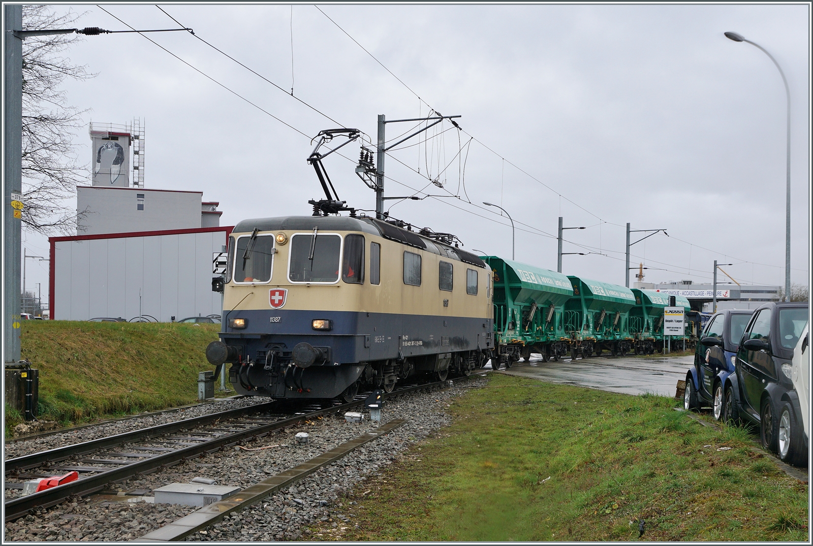Die IRSI/IGE  Rheingold  Re 4/4 II 11387 (Re 421 387-2) im Dienste der BAM MBC verlässt mit ihrem Kieszug nach Apples das Industriegelände bei Gland. 

22. Feb. 2024