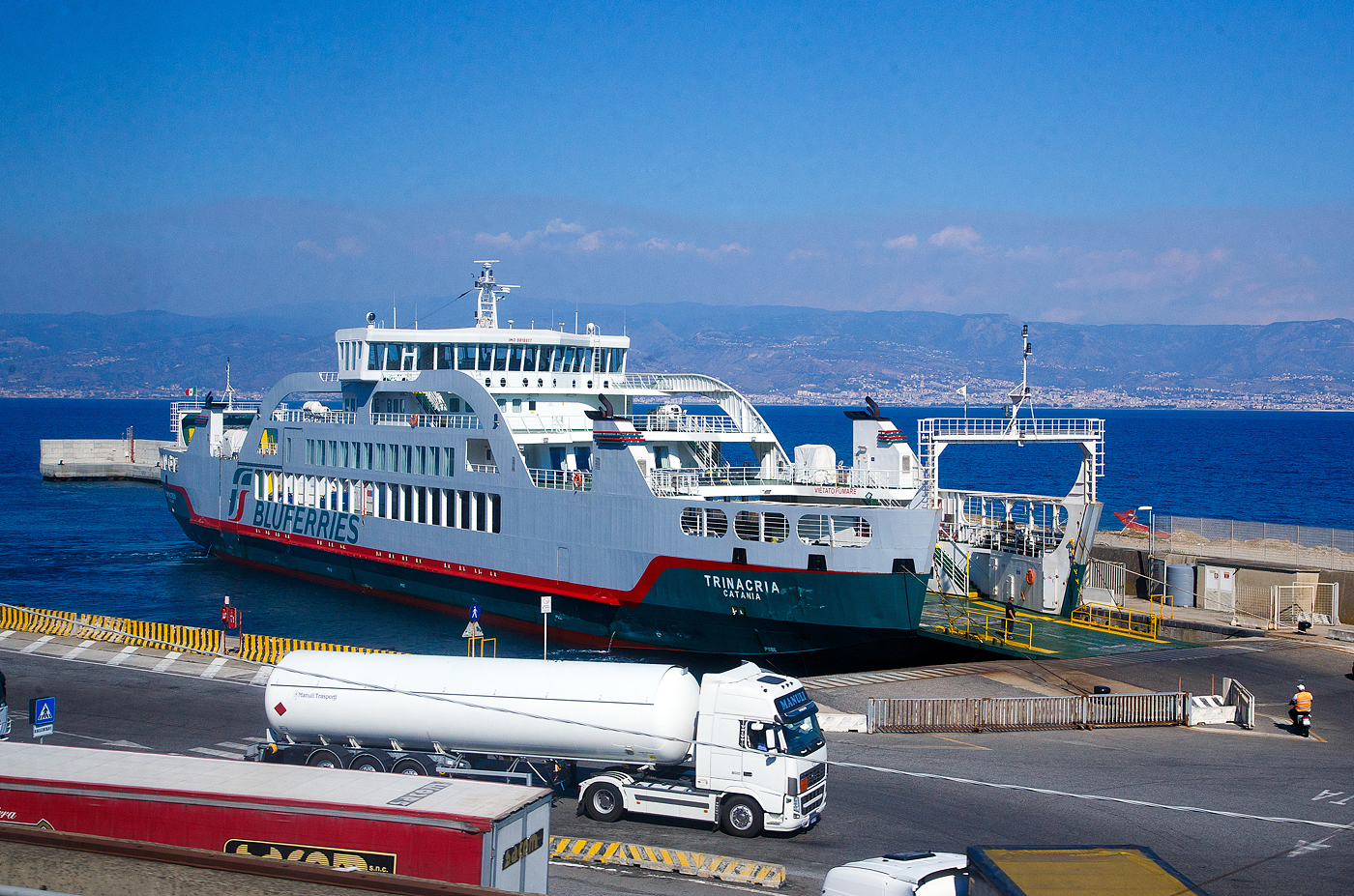 Die TRINACRIA (IMO 9818917) ein Ro-Ro Fährschiff der Bluferries (ein Unternehmen der Gruppe FS - Ferrovie dello Stato Italiane), liegt am 20.07.2022 beim Bluferries Fährterminal in Tremestieri (Messina). Diese Fähre ist ausschließlich für die Beförderung von Radfahrzeugen und Passagieren in der Straße von Messina. Sie kann keine Eisenbahnwaggons transportieren.

Die Fähre (Schiff) wurde von der griechischen Werftder Megatechnica SA in Perama (Griechenland) gebaut. Am 6. Februar 2019 wurde es offiziell in Dienst gestellt. Das Schiff wird nur für den Transport von Radfahrzeugen und Passagieren verwendet und ist mit vier um 360° drehbaren Strahlrudern ausgestattet, die ihm eine große Manövrierfähigkeit ermöglichen.

TECHNISCHE DATEN:
Vermessung (Bruttoraumzahl): 2.400 BRT
Länge: 97 m
Breite: 18 m
Antrieb: 4 x Z-Antrieb VZ 900-CR
Geschwindigkeit: 16 Knoten (29,63 km/h)
Ladekapazität: 150 Pkw (alternativ 23 Lkw)
Zugelassene Passagierzahl: 400
