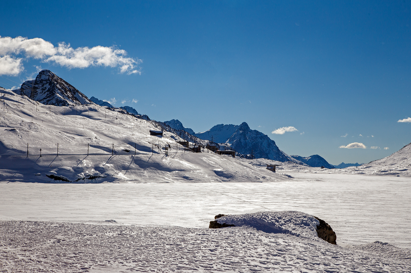 Ein winterlicher letzter Blick aus dem Bernina-Zug über den Lago Bianco hinweg auf Ospizio Bernina am 20 Februar 2017. Durch den Schnee auf dem zugefrorenen Lago Bianco ist dieser hier wahrhaft weiß. 

Der RhB Bahnhof Ospizio Bernina (Bernina-Hospiz) ist mit 2.253 m ü. M. die höchstgelegene Bahnstation im Netz der Rhätischen Bahn und damit auch die höchste Eisenbahn-Alpenüberquerung und das sogar als reine Adhäsionsbahn.
