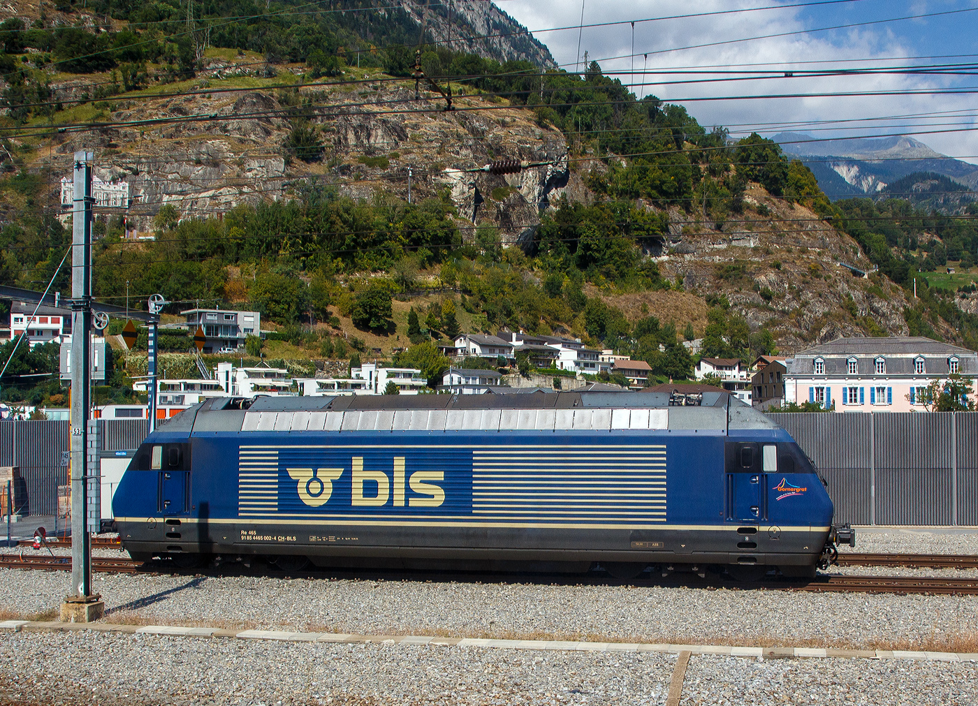 Noch im alten originalen Dunkelblau und somit noch nicht modernisiert, die BLS 465 002-4 „Görnergrat“ (91 85 4465 002-4 CH-BLS) seht am 08 September 2021 in Birg, aufgenommen aus einem IC.

Die BLS Re 465 stellen eine Weiterentwicklung der SBB Re 460 dar. Wie diese hat sie GTO-Thyristoren als Ventile im Stromrichter und Drehstrom-Asynchronmotoren. Der Unterschied liegt in der Umrichteranlage. Im Fall der Re 460 der SBB besteht ein Traktionsstromrichter (zwei je Lok, ein Gerät pro Drehgestell) aus zwei Vierquadrantenstellern die den Zwischenkreis parallel versorgen und einem Motor-Wechselrichter der zwei Motoren parallel speist. Die Stromrichter der BLS Re 465 gruppieren sich zu drei Vierquadrantenstellern parallel an einem Zwischenkreis mit zwei Wechselrichtern, je einen Motor im Drehgestell speisend. Somit lässt sich eine schleudernde Achse schneller und effektiver wieder in einen normalen Lauf bringen. Wurde bei der Entwicklung der Re 460 auf Dreipunkt-Stromrichter gesetzt, wurde im Gegensatz dazu die Re 465 mit Zweipunkt-Technik ausgestattet. Die Zwischenkreisspannung senkte man entsprechend von 3,5 kV (Re 460) auf 2,8 kV (Re 465). Zudem besitzt die Re 465 sechspolige Asynchron-Fahrmotoren, die Re 460 hingegen nur vierpolige Asynchronmotoren. Daraus resultiert eine gegenüber der Re 460 erhöhte Dauerleistung von 6.400 kW (Stundenleistung von 7000 kW). Die Radsätze im Drehgestell stellen sich radial zum Gleisbogen ein.

Zudem ist die Re 465 im Unterschied zur Re 460 mit der Vielfachsteuerung des Systems IIId und (mit Übergangskabel) BLS/BBC ausgerüstet. Dies erlaubt die Vielfachsteuerung zum Beispiel mit Re 4/4II, Re 4/4III, Re 6/6, Re 425 oder Ae 415.

In den Jahren 2019 bis 2022 wurden die Lokomotiven einem Refit unterzogen. Darin enthalten waren unter anderem der Einbau der Vielfachsteuerung ZMS für den Güterverkehr mit Traxx- und Vectron-Lokomotiven und ETB (Ethernet Train Backbone) für den Autoverlad am Lötschberg. Die Kästen wurden saniert und neu in hellem BLS-Lindengrün mit blauem Logo lackiert. Die Arbeiten wurden in der eigenen Werkstätte der BLS in Bönigen ausgeführt, die Kosten beliefen sich auf 20 Millionen Franken.