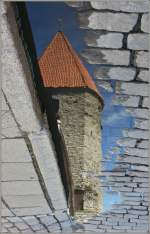 Ein Turm der Stadtmauer von Tallin spiegelt sich in der Wasserpftze.